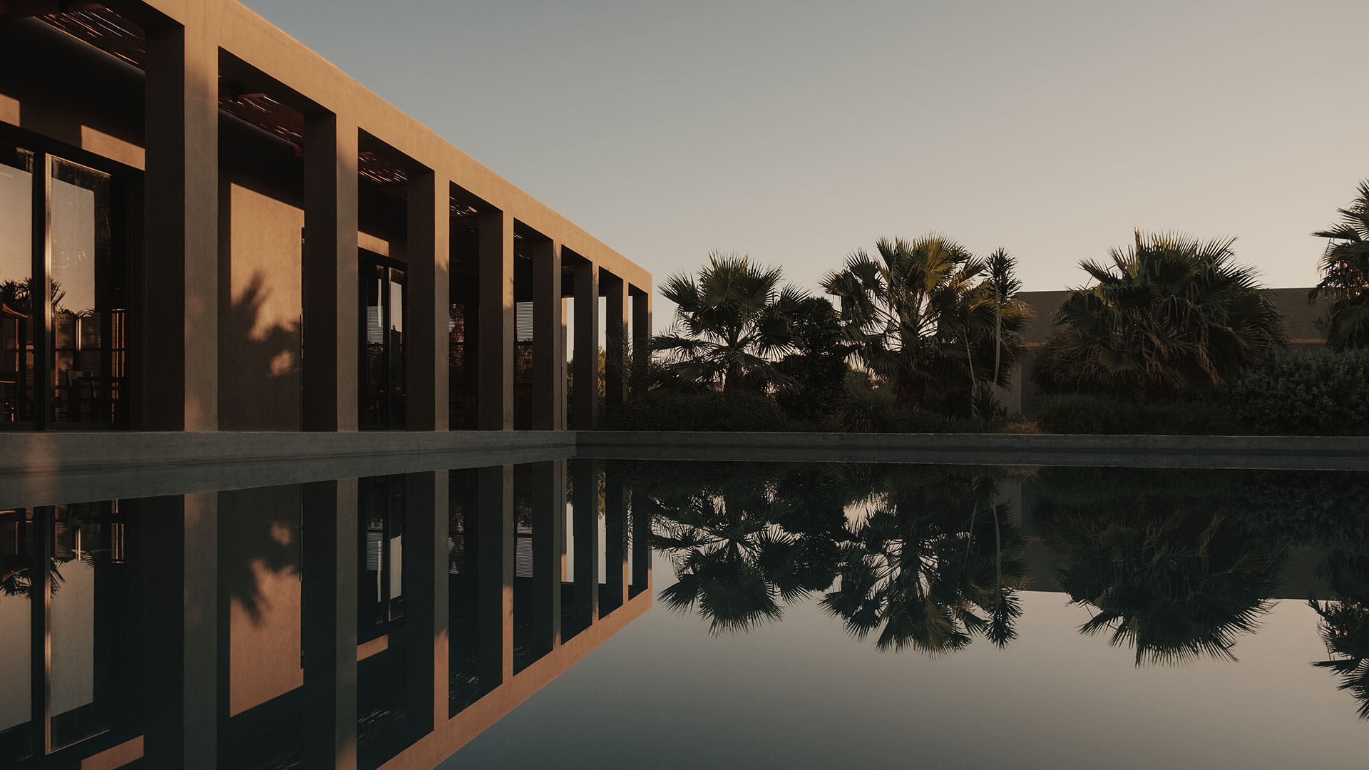 Modern hotel architecture reflected in water with palm trees, calm and balanced setting 