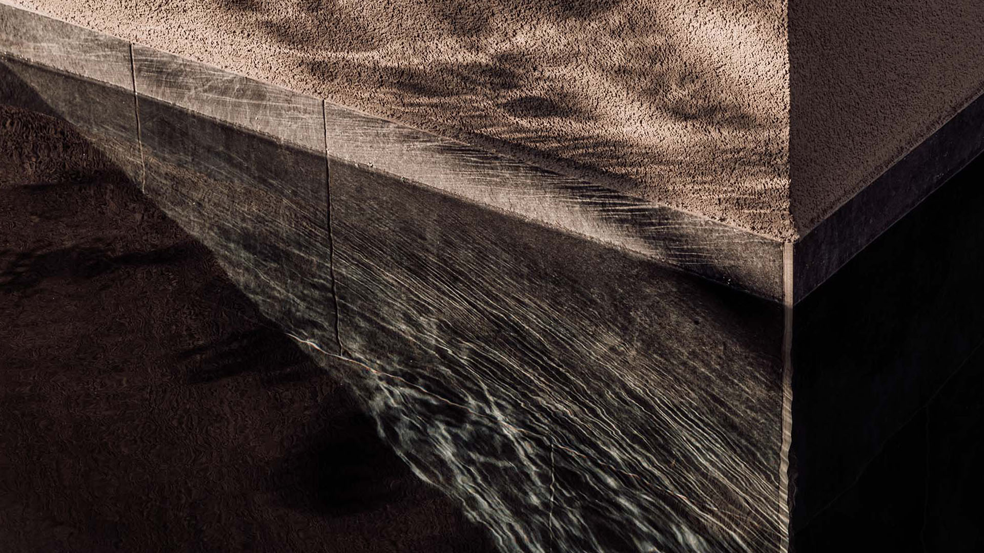 Water flowing over stone edge as a minimal architectural feature in a hotel design concept